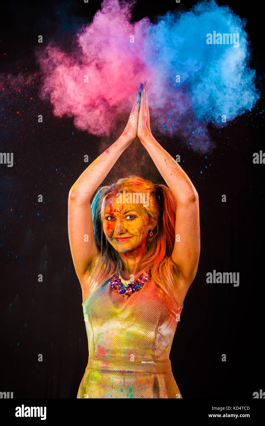 Beautiful young woman with colored powder over dark backgrond Stock Photo