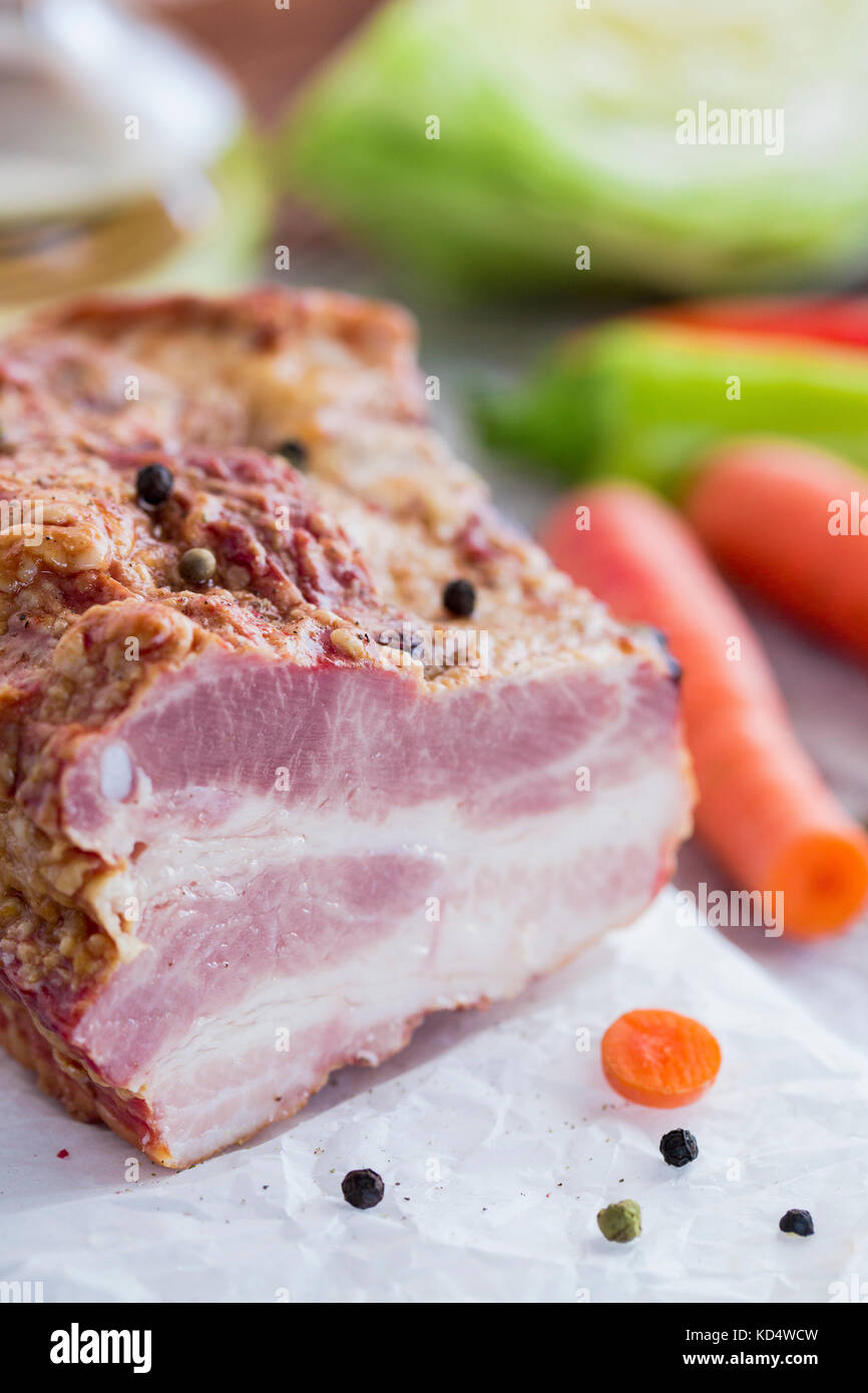 Smoked Meat with Vegetables on Brown Wooden Table. Smoked Raw Layered Meat with Raw Cabbage, Green and Red Peppers, Carrots, Sunflower Oil prepared fo Stock Photo