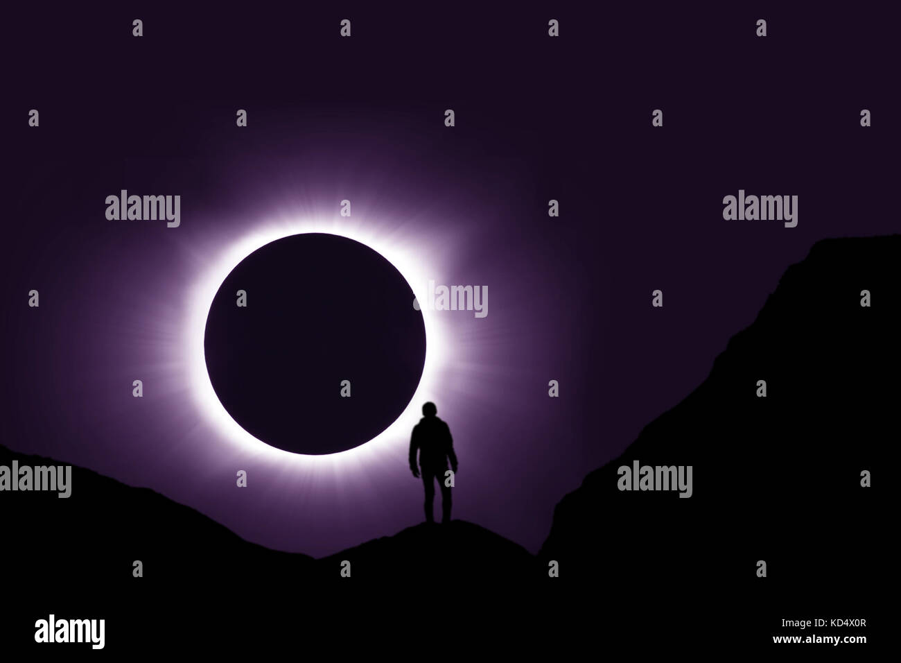 Full Solar Eclipse With Man Standing On Mountain In Foreground Stock Photo