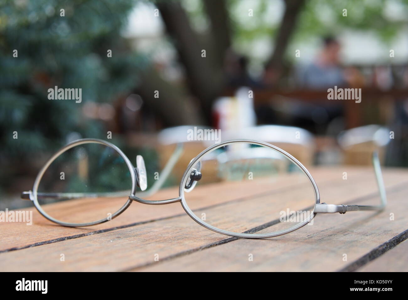 Close up of a pair of reading glasses on an outdoor pub table. Stock Photo
