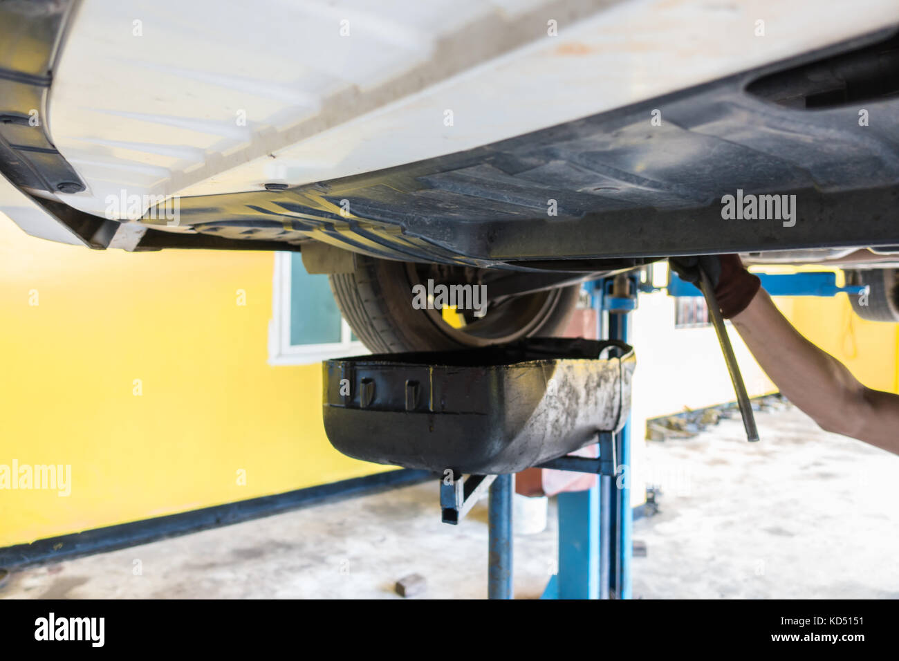 Mechanic draining engine oil from a car for an oil change at an auto shop Stock Photo