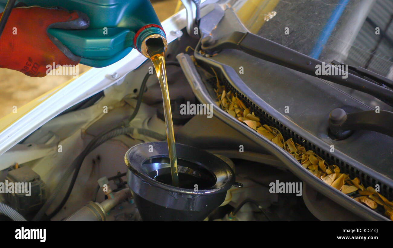 Mechanic draining engine oil from a car for an oil change at an auto shop Stock Photo