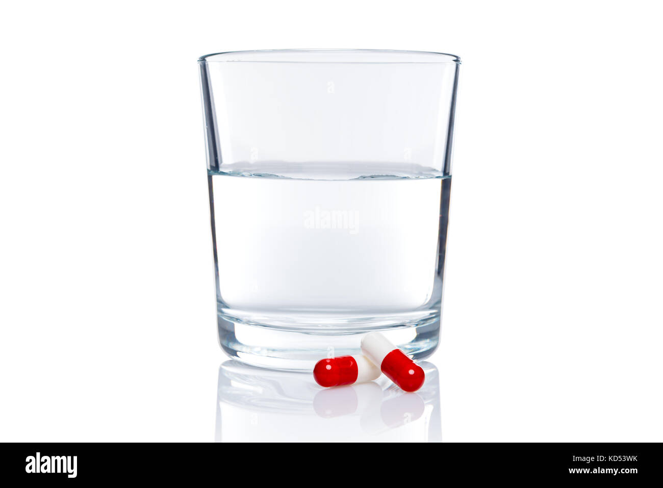 Glass of water and two pills isolated on white background with clipping path. Stock Photo