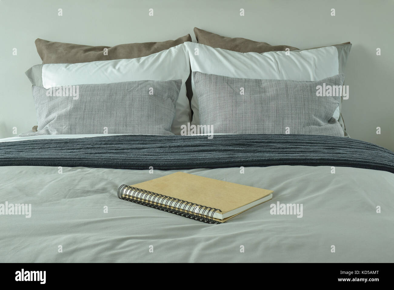 Notebook on bed with gray color scheme bedding Stock Photo - Alamy