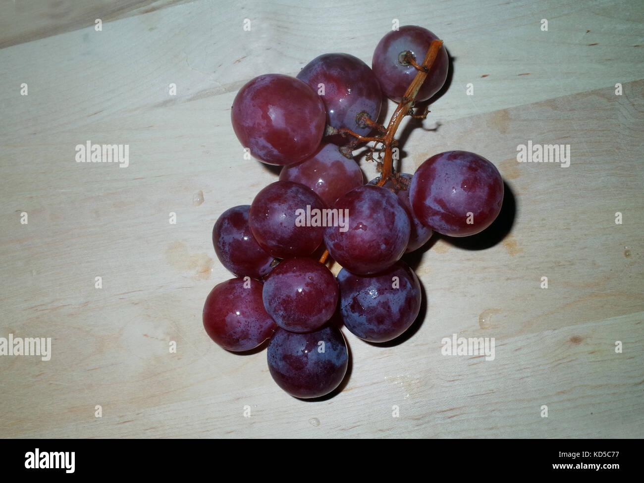 Red grape "cardinal" (vitis vinifera) on wooden table Stock Photo