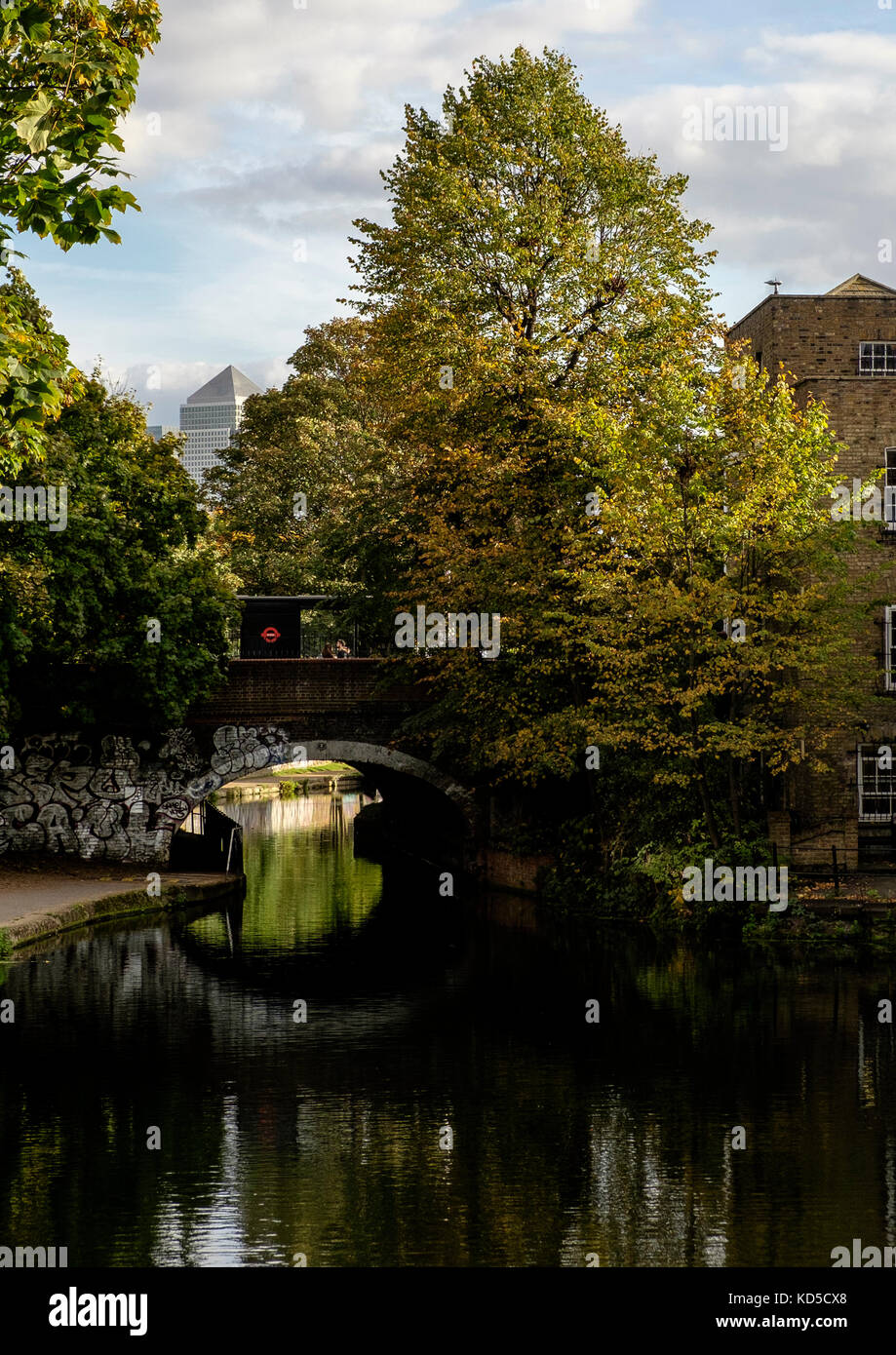 Looking towards Canary Wharf from Mile End Lock on the Regents Canal, London. The bridge carries the A11, Mile End Road. Stock Photo