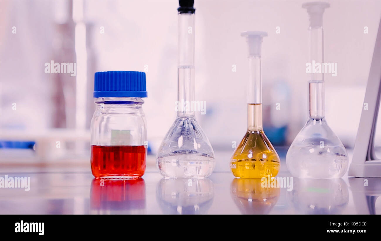 Laboratory flasks and beakers with liquids of different colors on lab