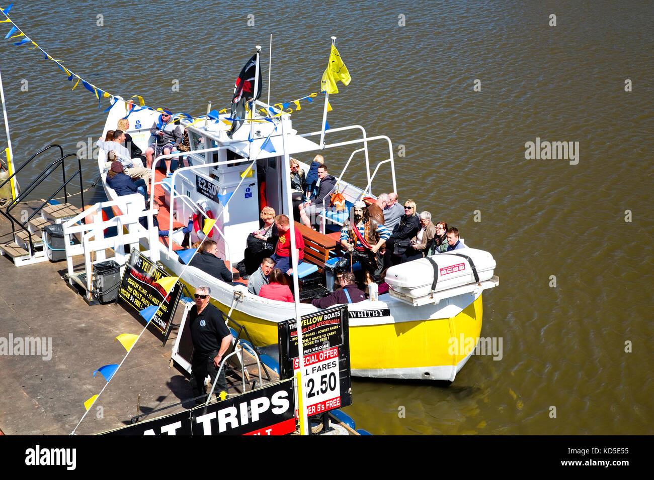 View of people sitting on a pleasure boat at Whitby pier waiting to set sail on a round the harbour seaside trip Stock Photo