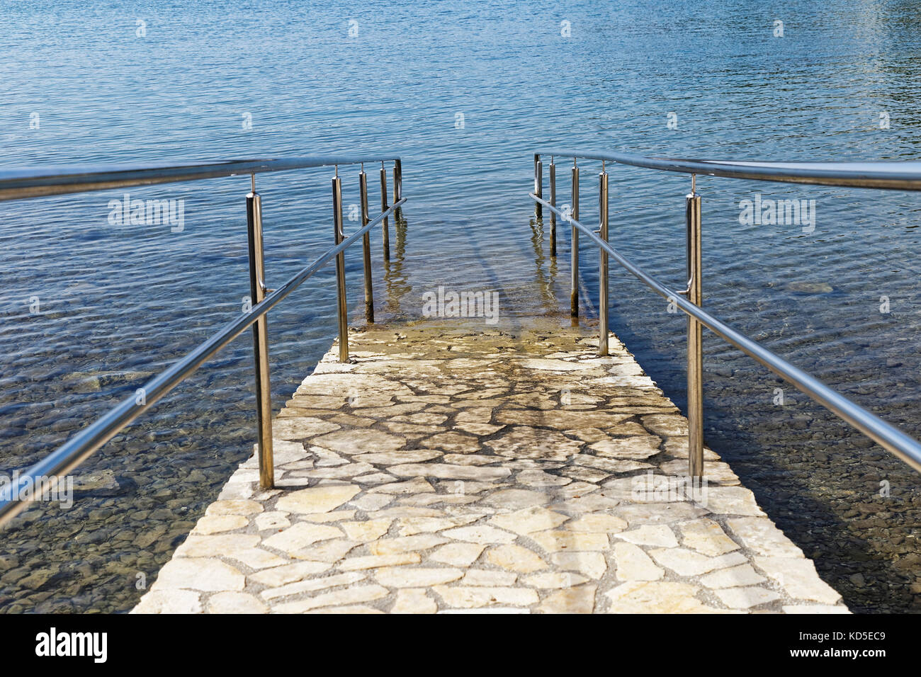 paved sea ramp with metal handrail Stock Photo