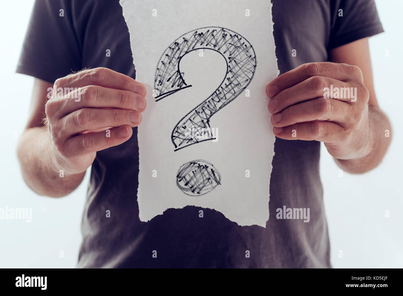 Question mark, looking for answers. Man holding paper with scribbled interrogation point, query, or eroteme punctuation Stock Photo