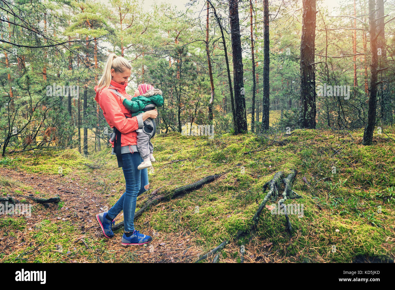 mother walking in the woods with baby in kangaroo bag Stock Photo