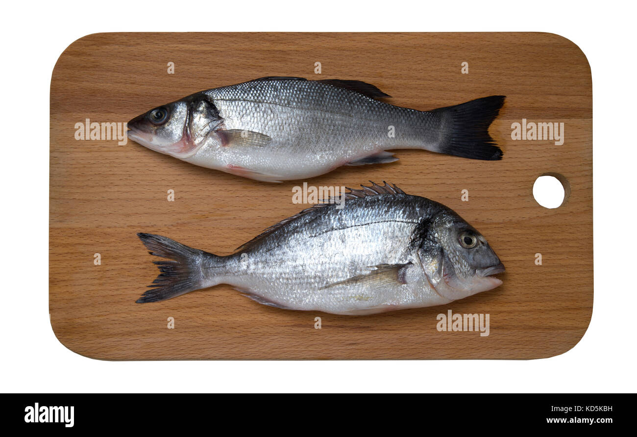 Fresh raw sea bass and dorado fish on wooden cutting board, top view Stock Photo