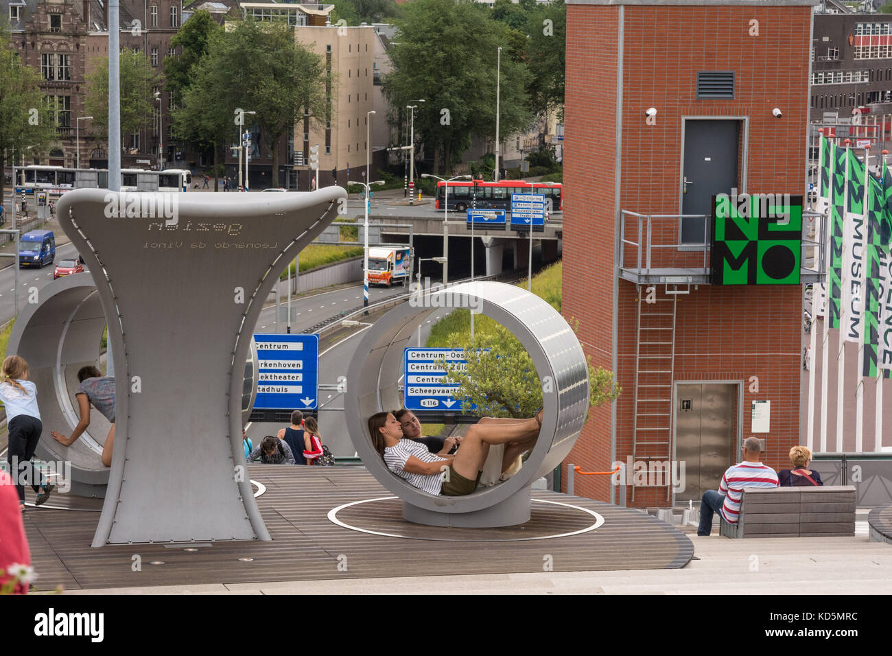 The view from the roof of NEMO, Amsterdam's Science Museum. Two young women sit inside interactive 'Solar Island' seating. Stock Photo