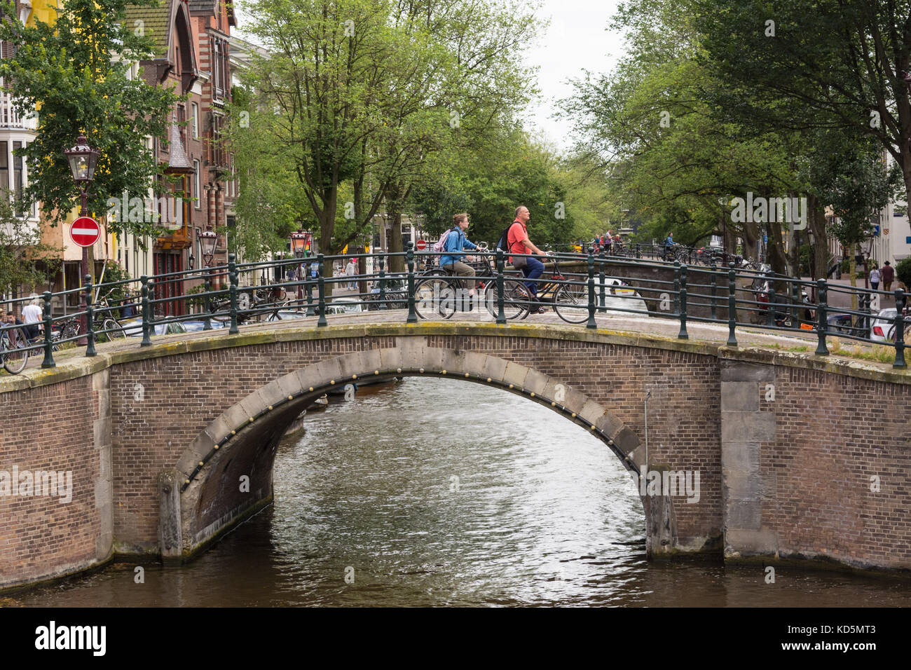 People cycling over a bridge on the Reguliersgracht canal in Amsterdam, The Netherlands Stock Photo