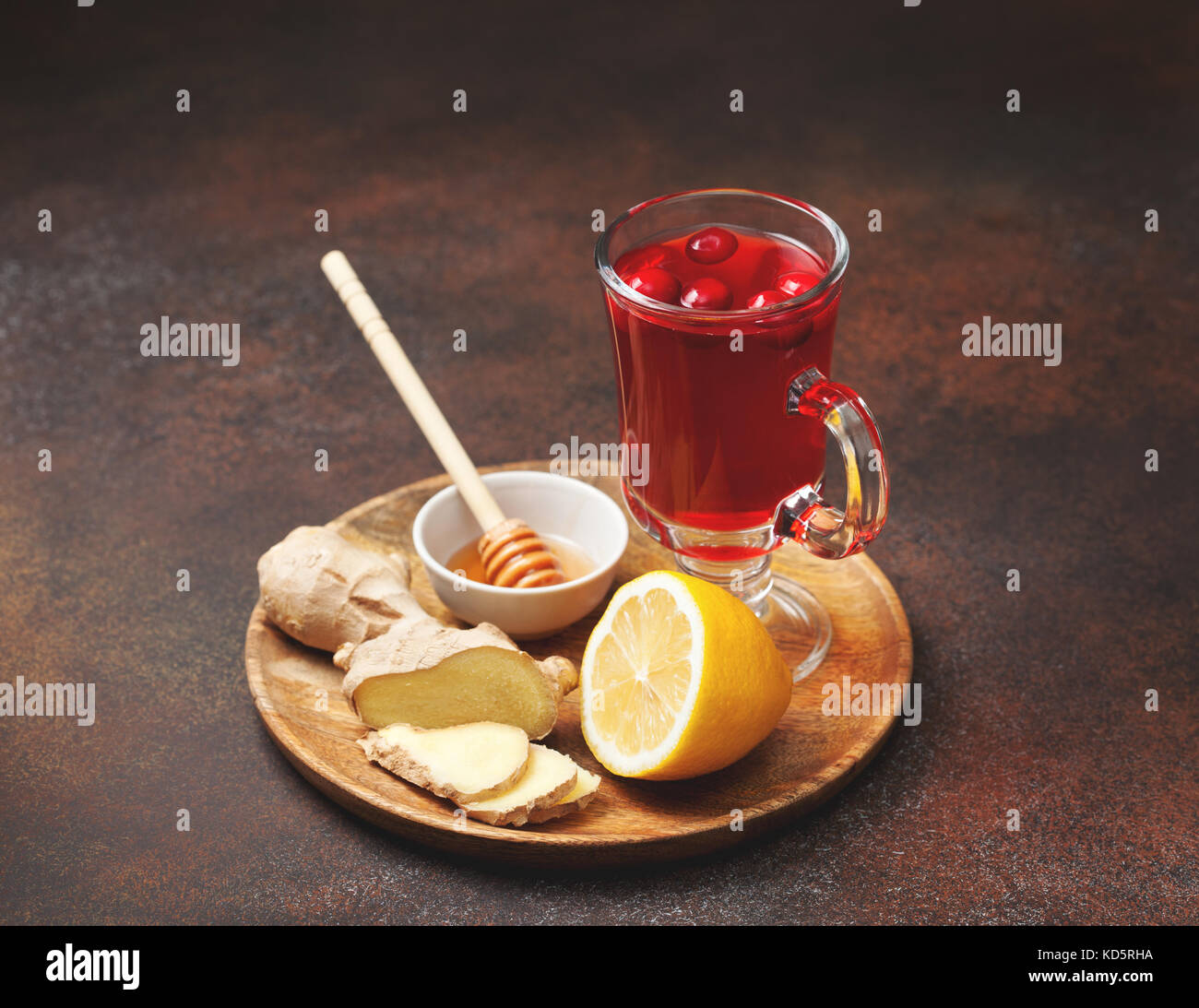 cranberry lemon ginger drink in a glass cup, honey, half a lemon, slices of ginger on an old background Stock Photo