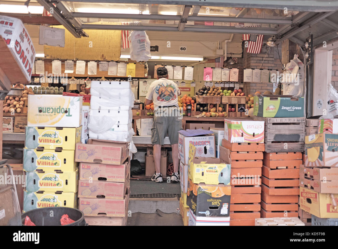 Food seller prepares a display during morning set-up at the West Side Market in the Ohio City neighborhood of Cleveland, Ohio, USA. Stock Photo