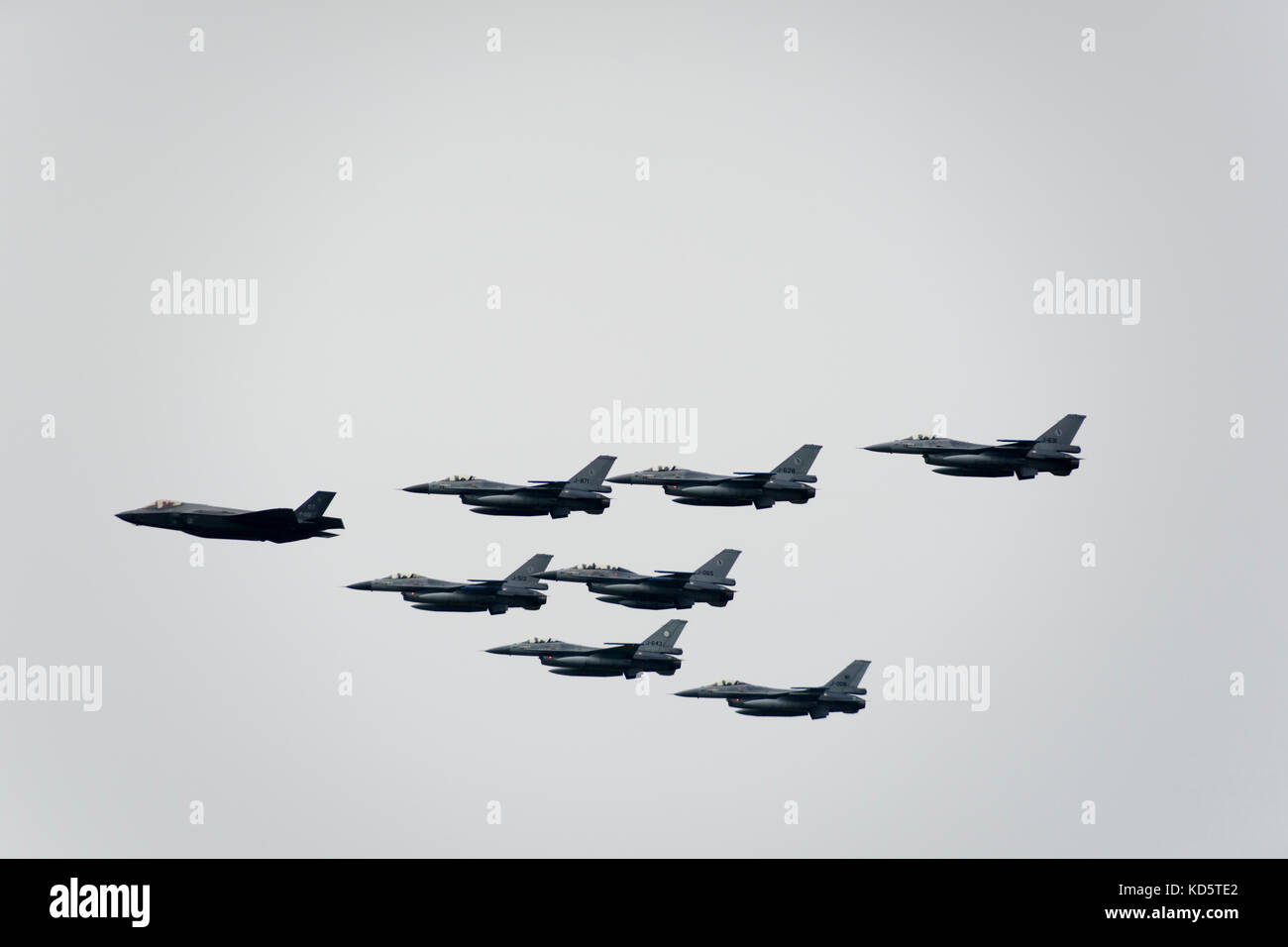 One F-35 and seven F-16 fighter jets in formation at the air show of the Royal Netherlands Air Force at the military air base in Leeuwarden, Netherlan Stock Photo
