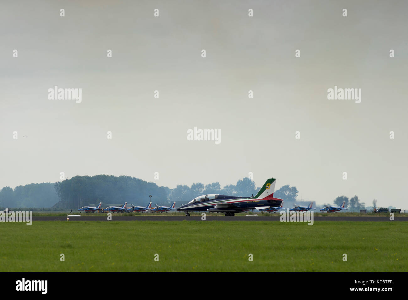 A plane of the Italian Aerobatic Team (Frecce Tricolore) rolls over the runway at the military airbase in Leeuwarden. In the background the planes of  Stock Photo