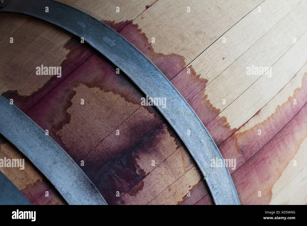 front view closeup of a wine oak wood barrel texture stained with red tannins Stock Photo