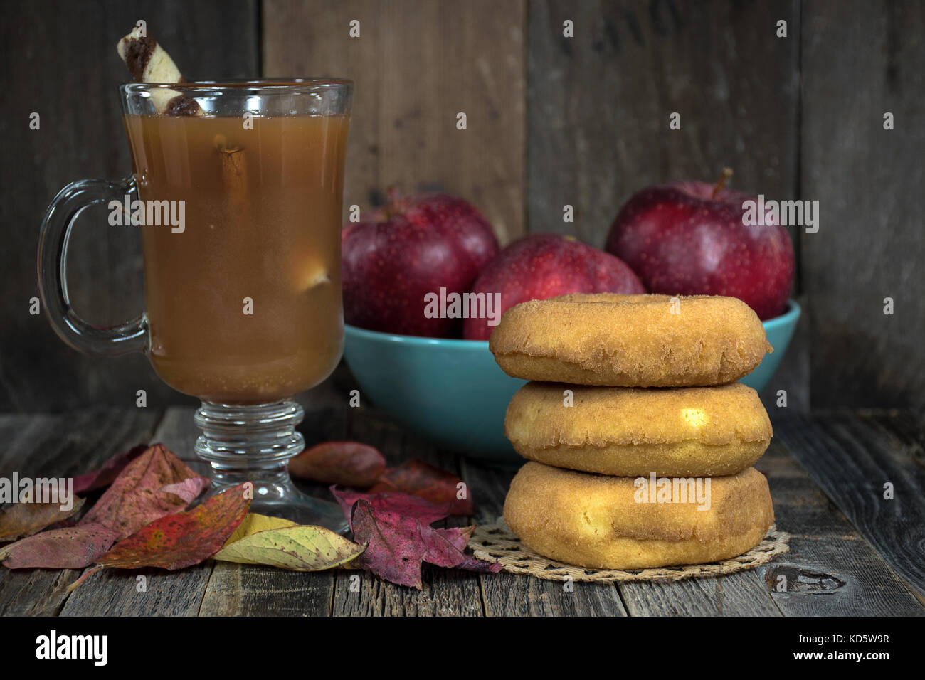 apple cider and donuts with autumn leaves and red apples on rustic wood Stock Photo