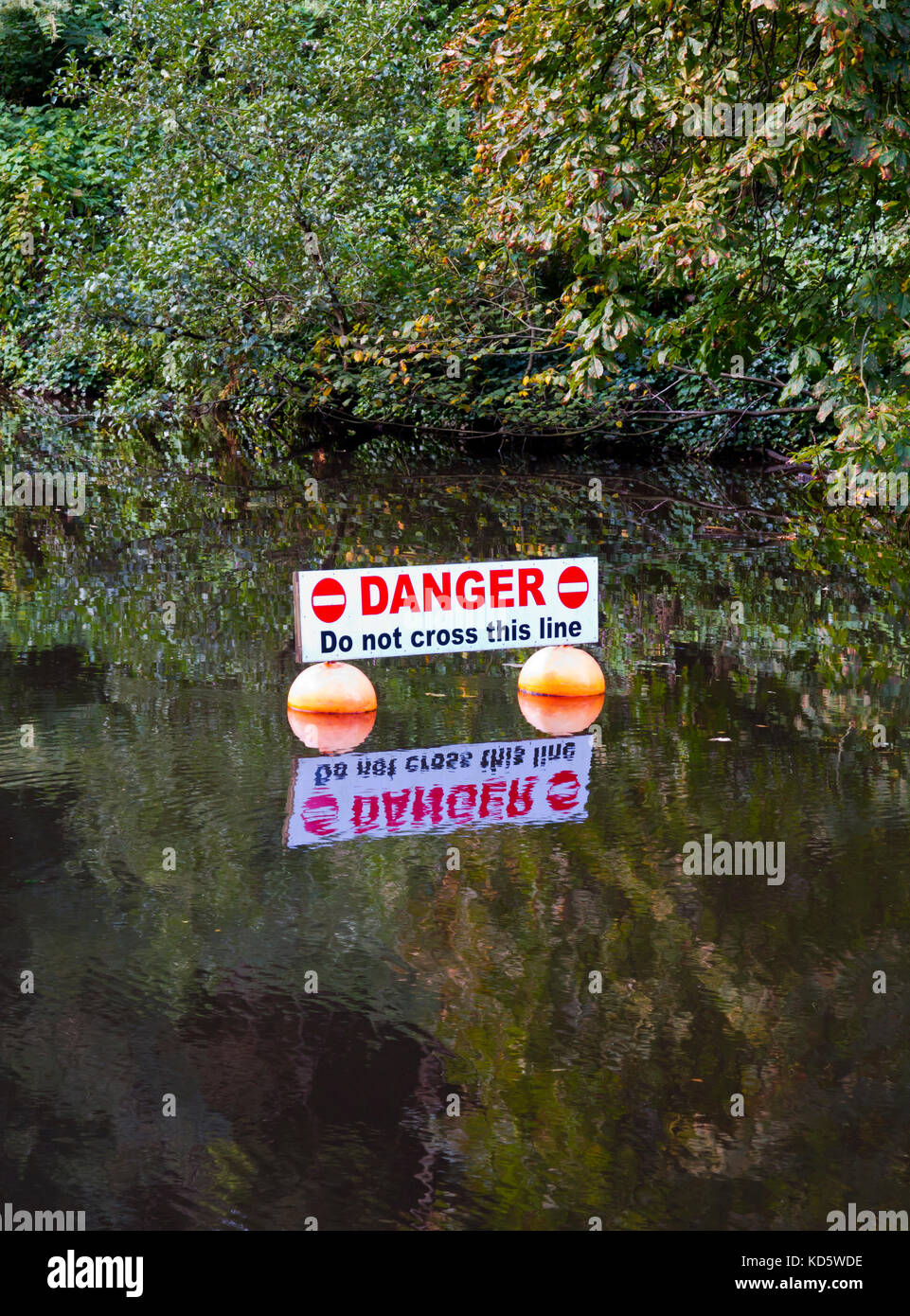 Danger Do Not Cross This Line sign in the River Derwent at Matlock Bath in the Derbyshire Peak District England UK Stock Photo