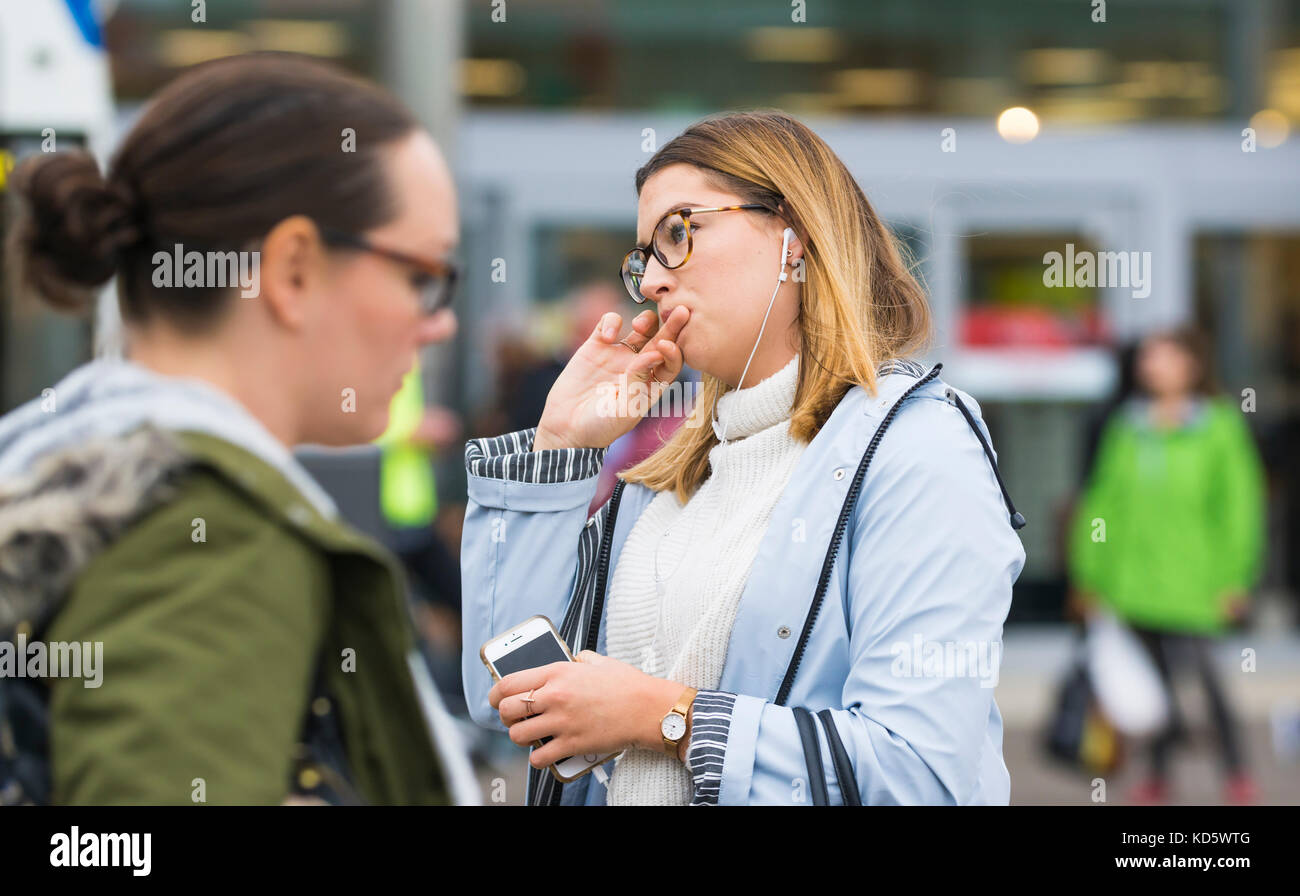 Young woman deep in thought while walking in a busy city and sucking on her finger. Stock Photo