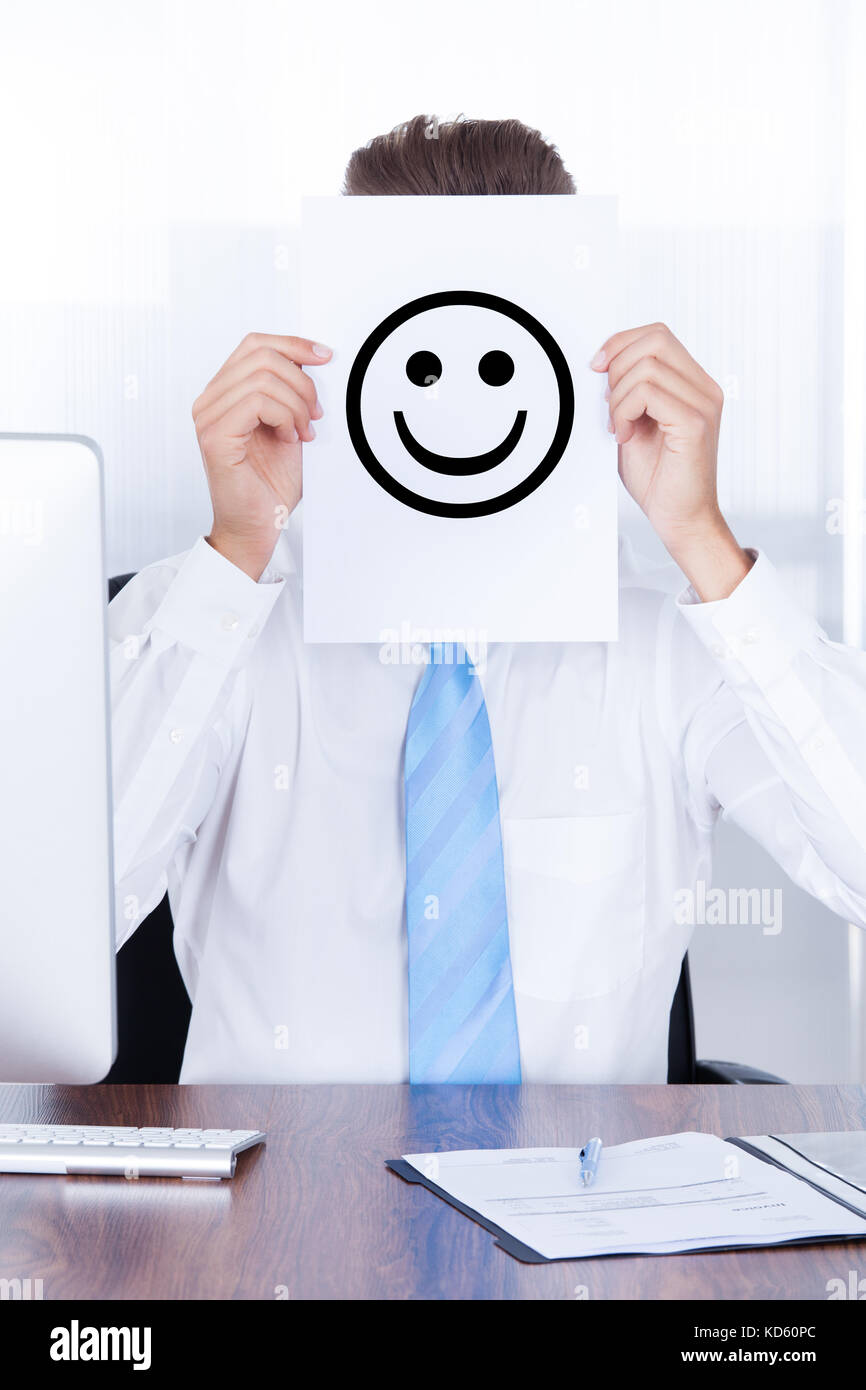 Close-up Businessman Holding Smile Emotion On Paper Over Face Stock Photo