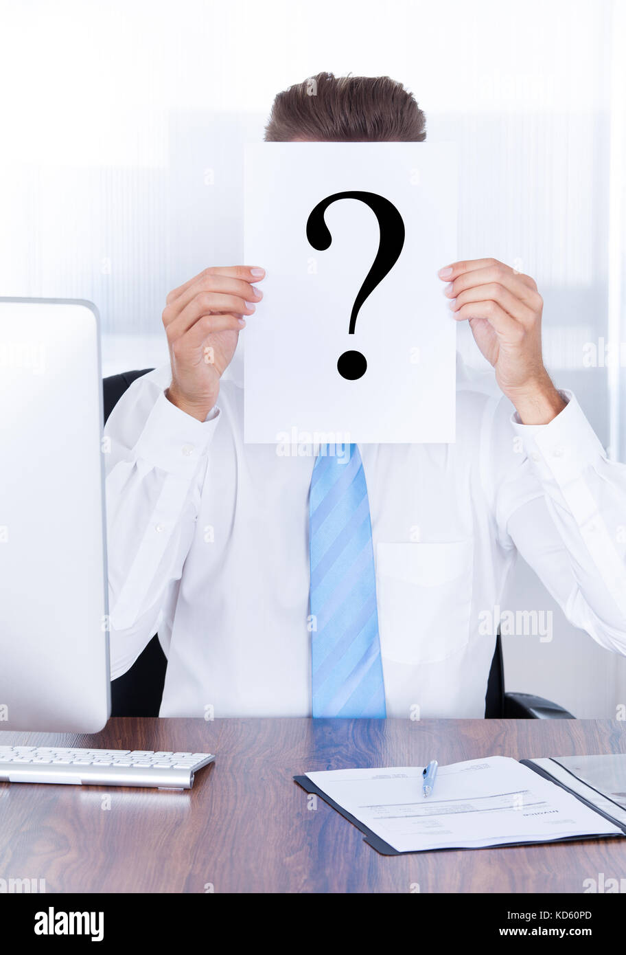 Businessman Holding Question Mark Sign On Paper In Front Of Face Stock Photo