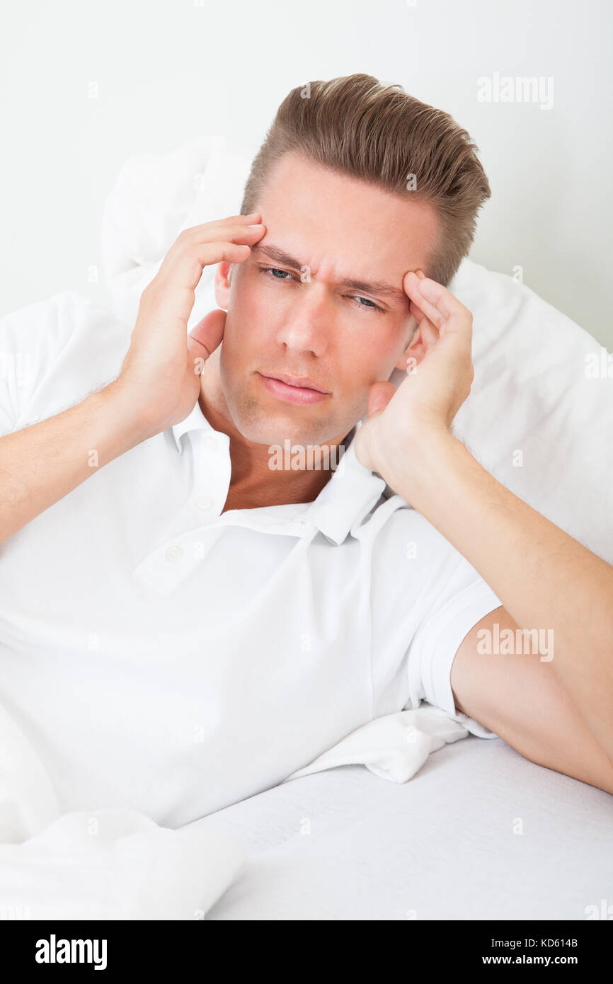 Young Man Lying On Bed Suffering From Headache Stock Photo Alamy