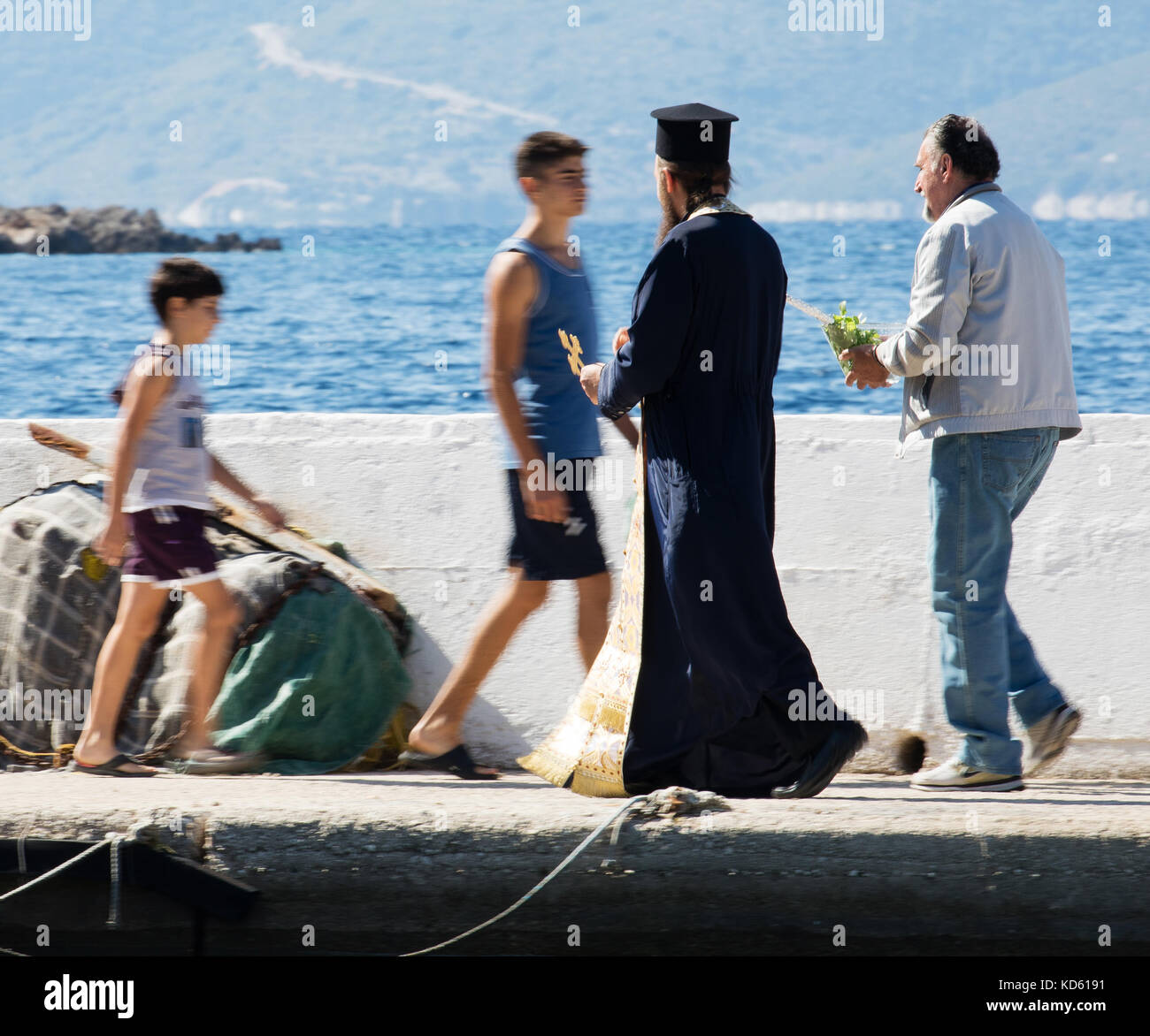 Young boys walking past a priest after blessing the catch at a fishing festival in Polis harbour near the village of Stavros on Ithaka Greece Stock Photo