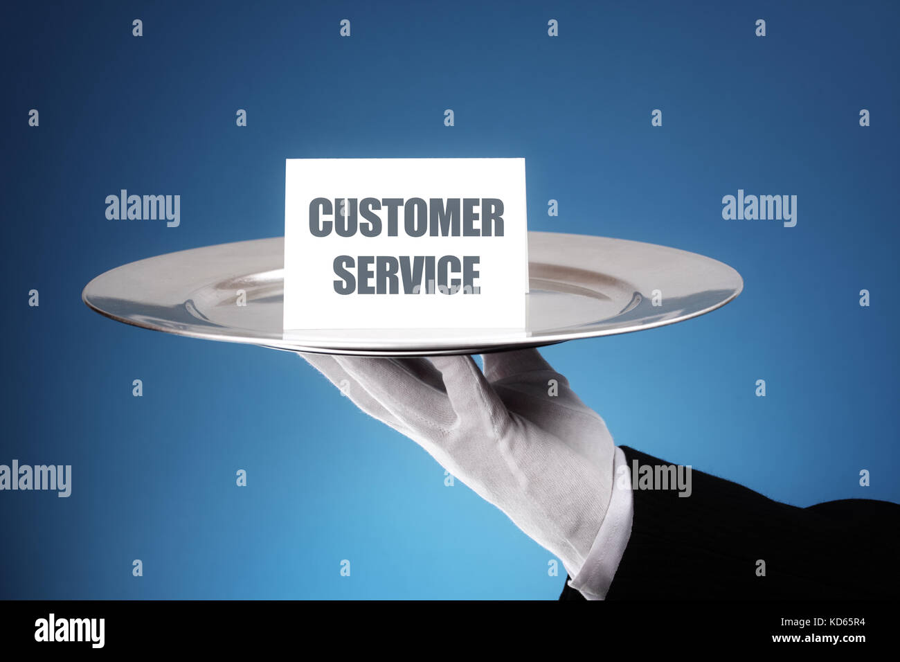 Butler or waiter holding a card reading customer service on a silver platter concept for first class or excellence Stock Photo