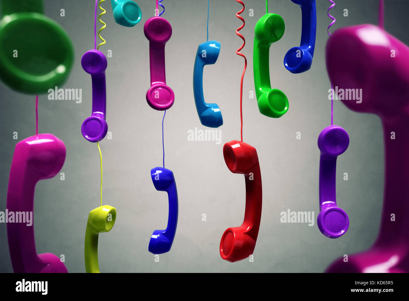 Red and multi-coloured telephone receiver hanging over gray background concept for on the phone, customer service, on hold or contact us Stock Photo