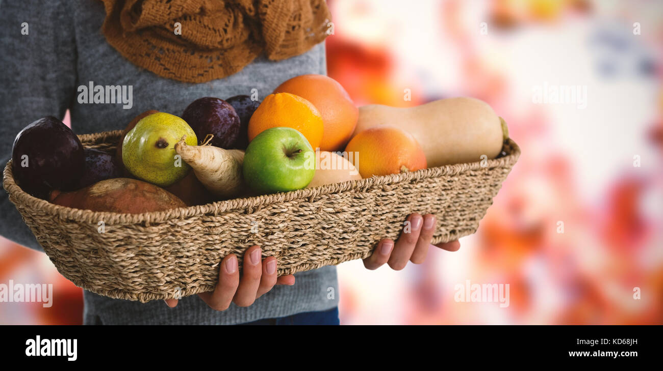 Mid section of woman holding fruits and vegetables in basket against ...