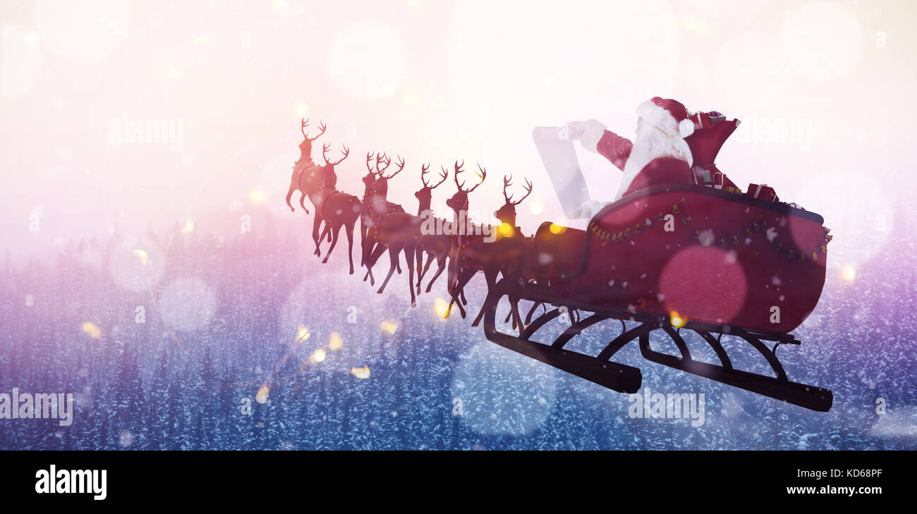 Santa Claus riding on sled during Christmas against snow covered trees during winter Stock Photo