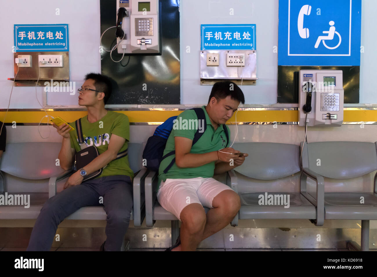 Chinese people and tourists with phones at Liangjiang International Airport in Guilin, China, Asia. Passengers charging smartphones on travel Stock Photo