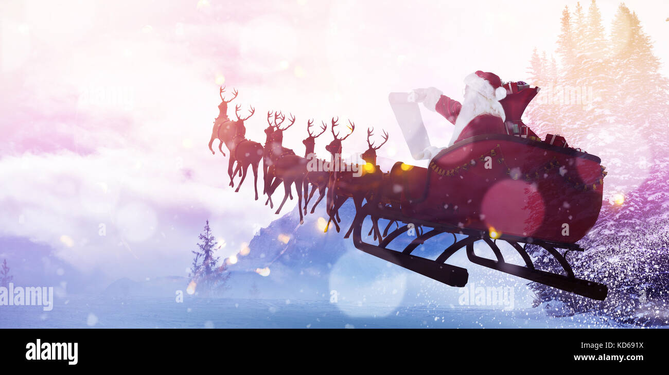Santa Claus riding on sled during Christmas against scenic view of snow covered trees and mountain Stock Photo