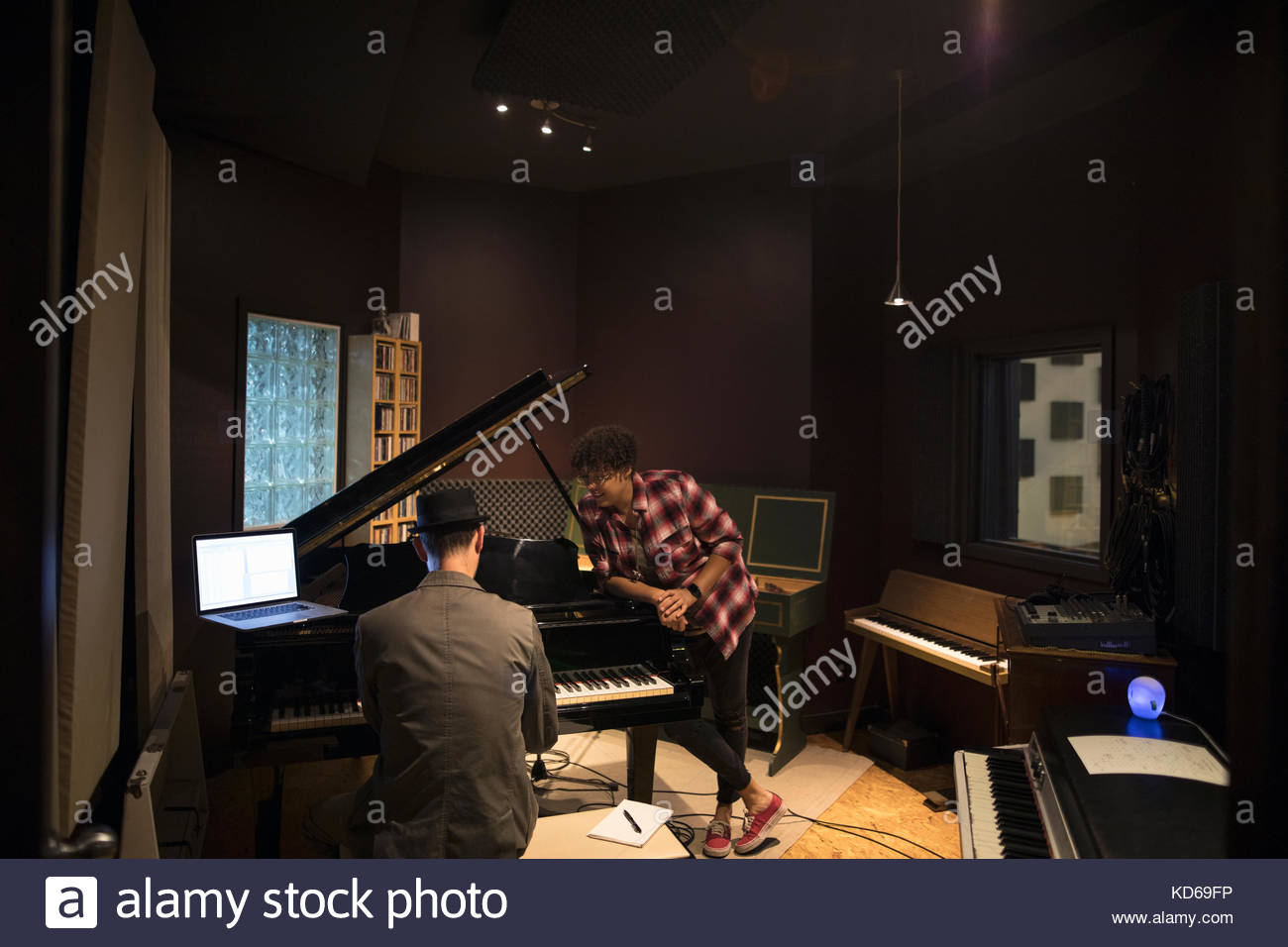 Pianists playing grand piano, writing music at laptop in recording studio Stock Photo