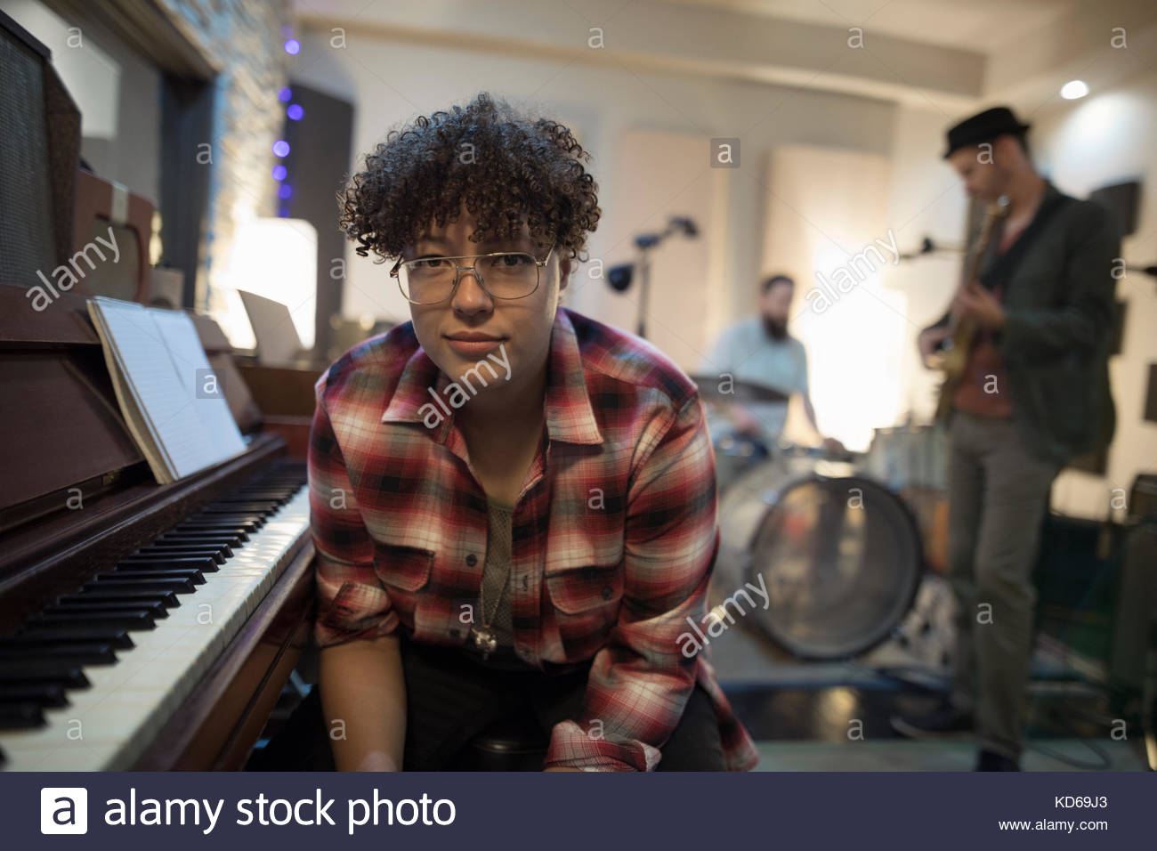 Portrait confident female pianist sitting at piano in recording studio Stock Photo