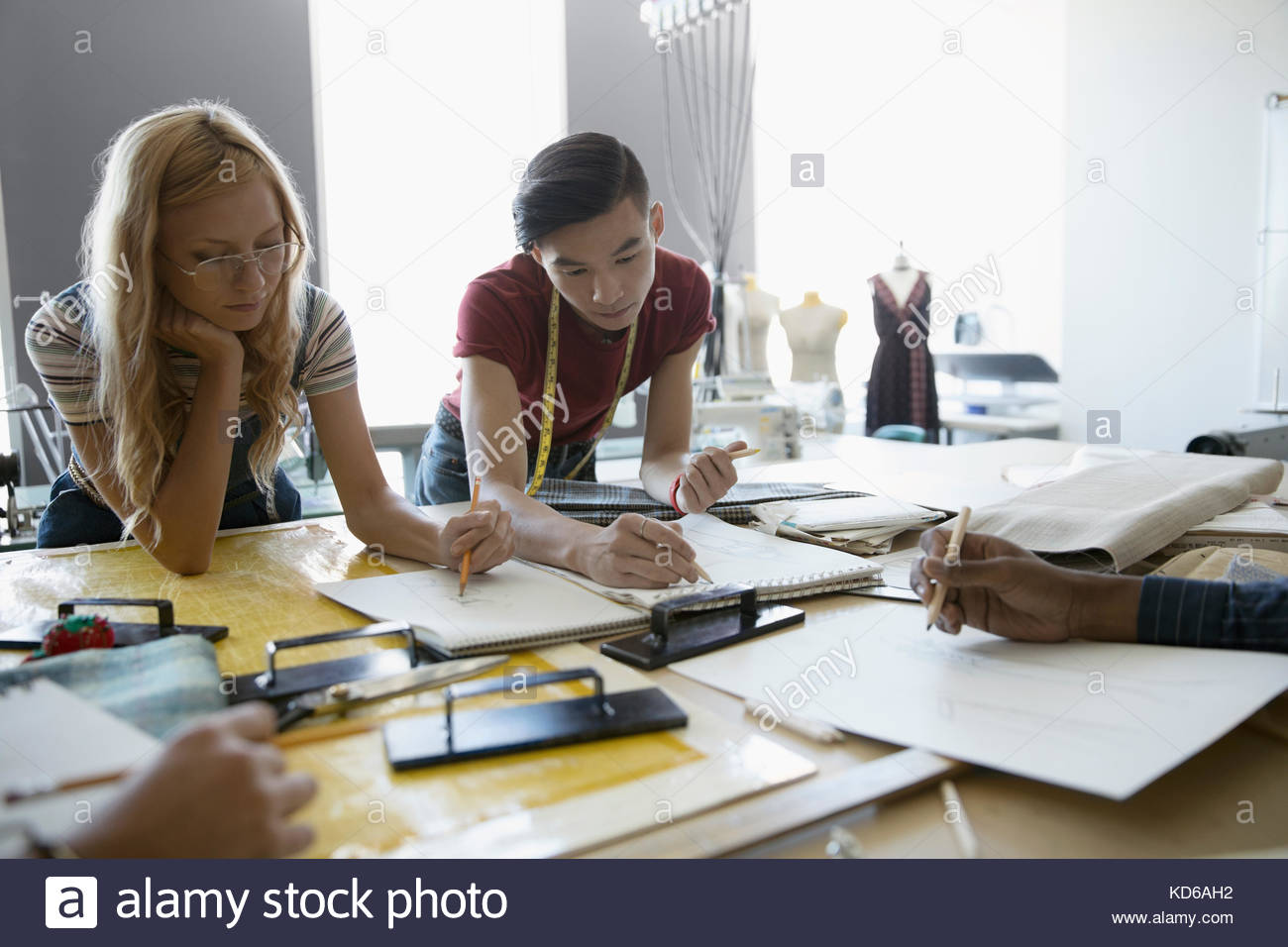 Fashion design students sketching at workbench in studio Stock Photo