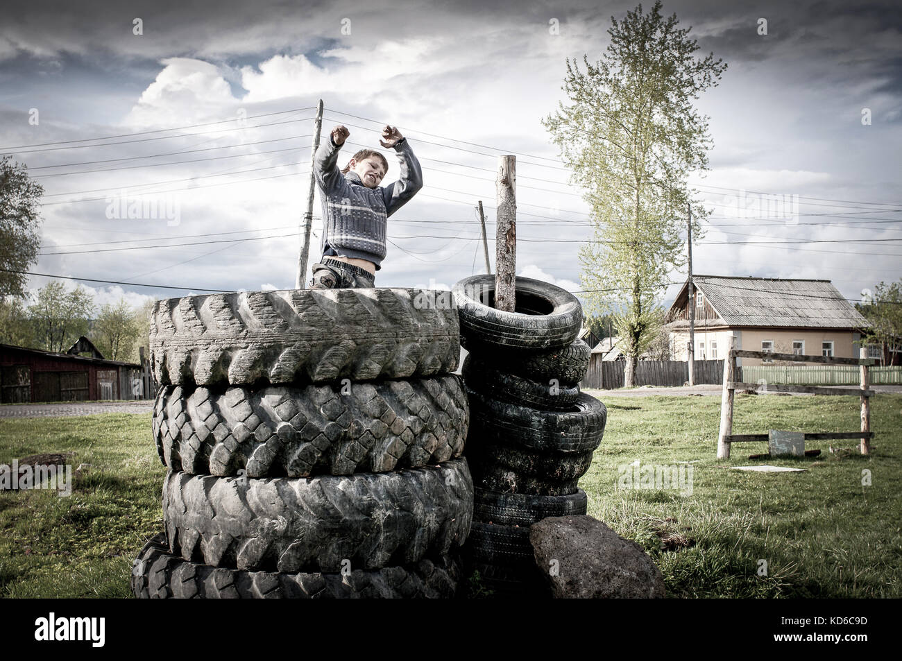 ALEXANDROVSK, RUSSIE - MAI 23 : Un jeune Russe joue dans des pneus servant d'air de jeux devant son habitation le 23 mai 2011 a Alexandrovsk, Russie. Stock Photo