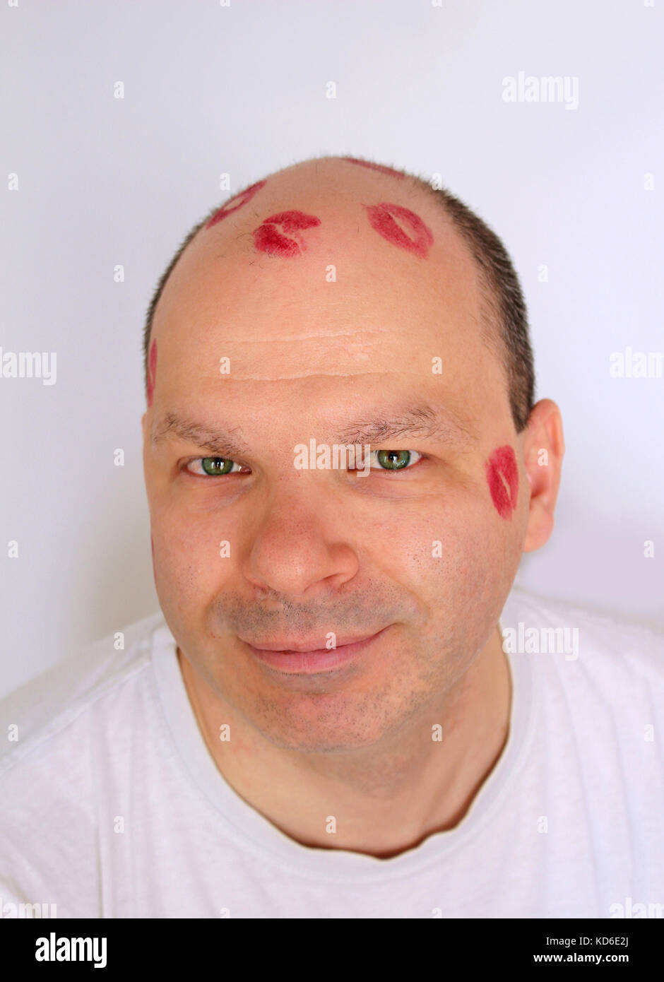 Young man with lipstick kisses marks on bald head Stock Photo