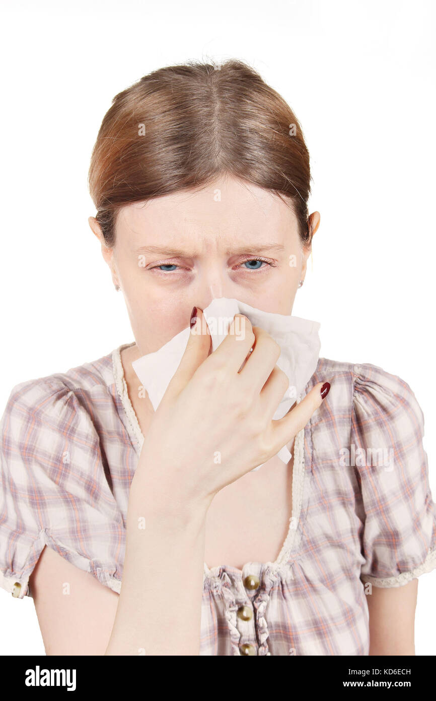 Young pale girl having a cold sneezing and whipping nose with paper tissue Stock Photo