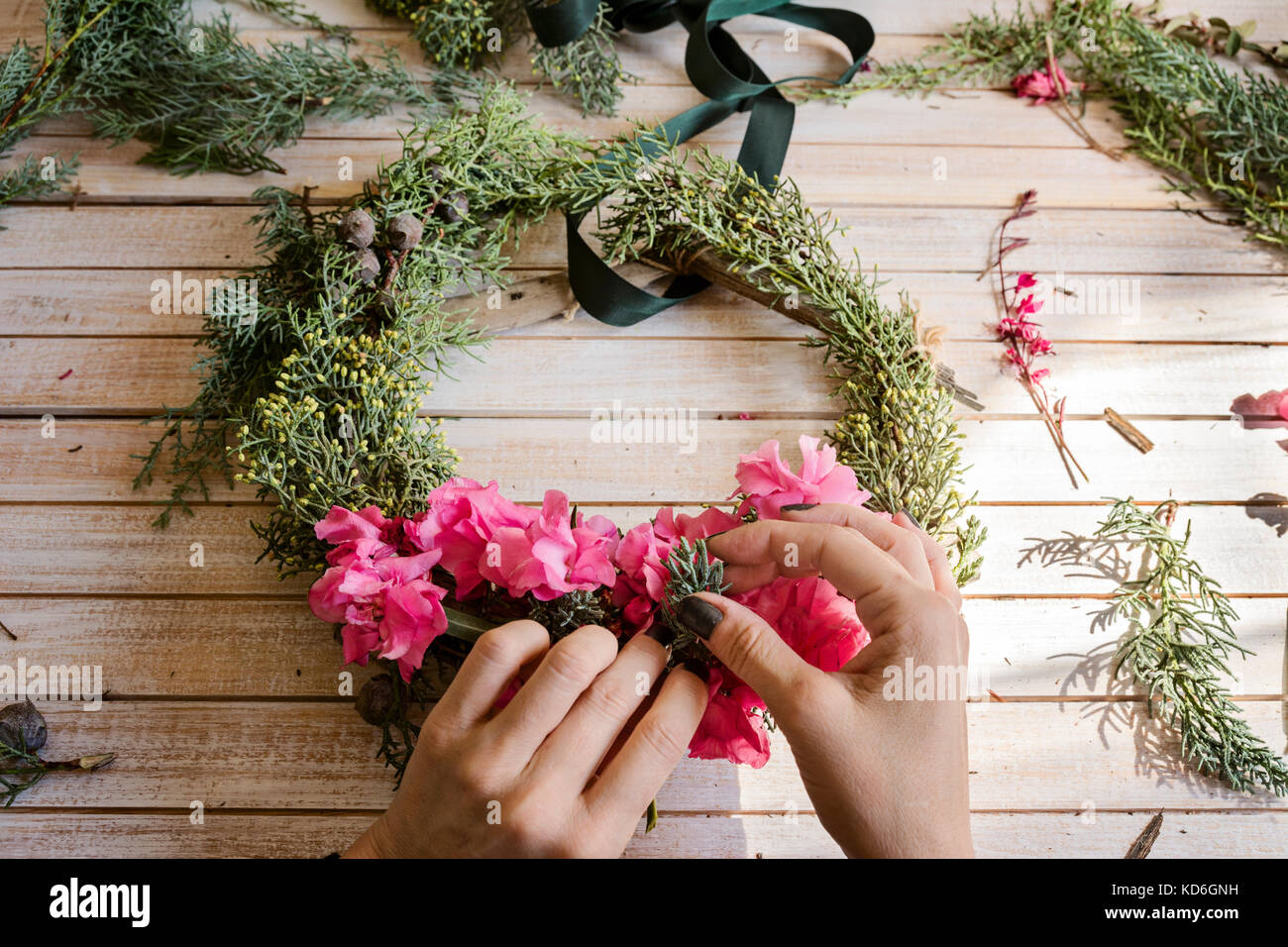 Florist at work Creating a wooden wreath with branches pine and pink