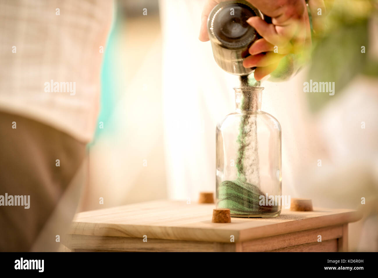 A couple pouring different colored sands into a jar, symbolizing their bond. Stock Photo
