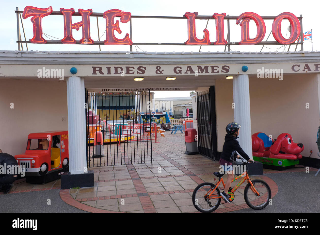 A child cycles past an amusement arcade in Worthing, West Sussex Stock Photo