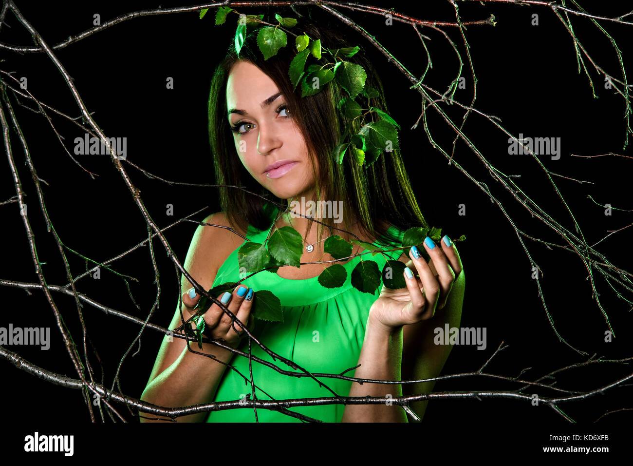 Pretty young woman in a green dress between dry branches Stock Photo