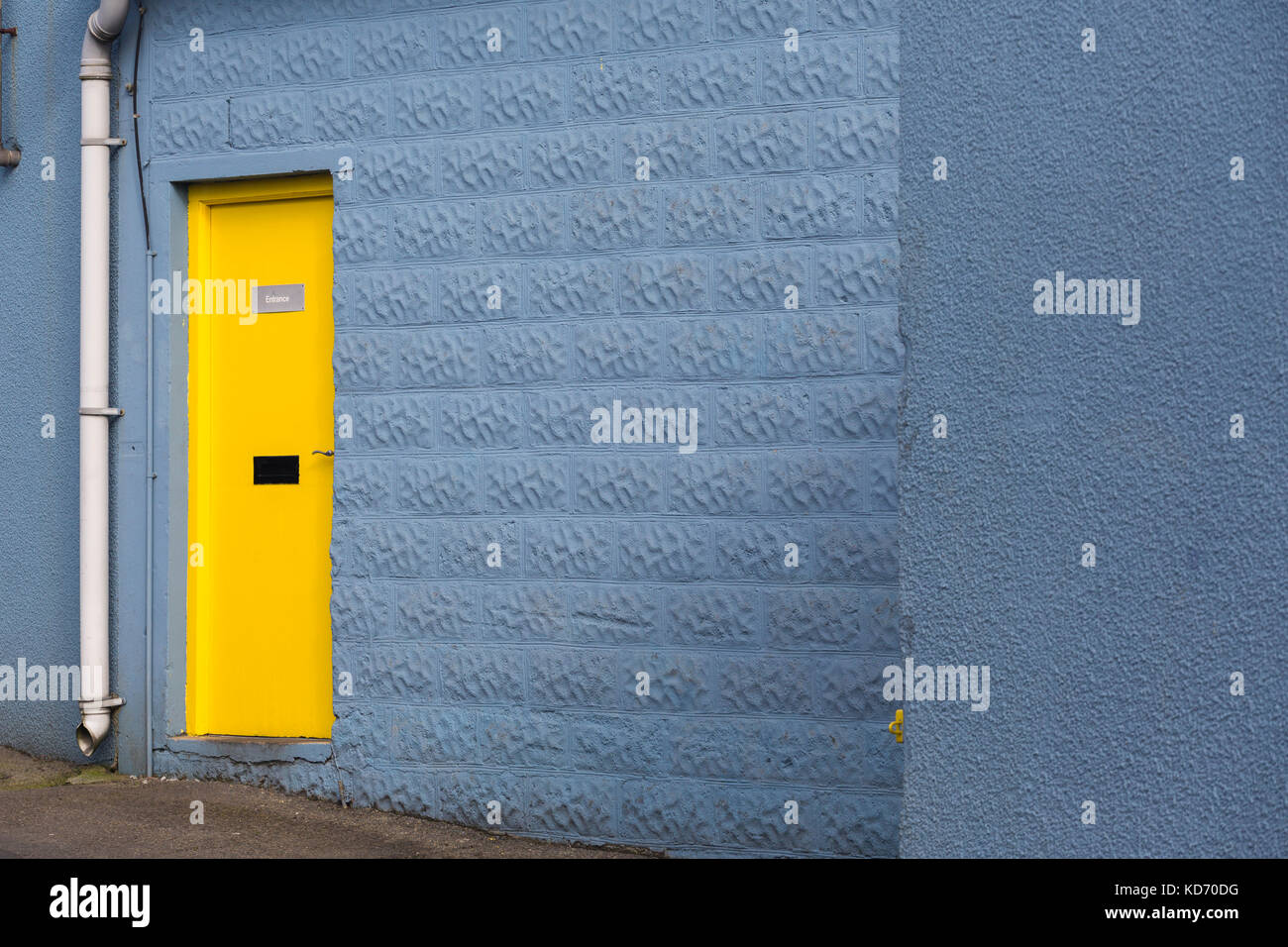 Bright colourful yellow door in blue wall Stock Photo