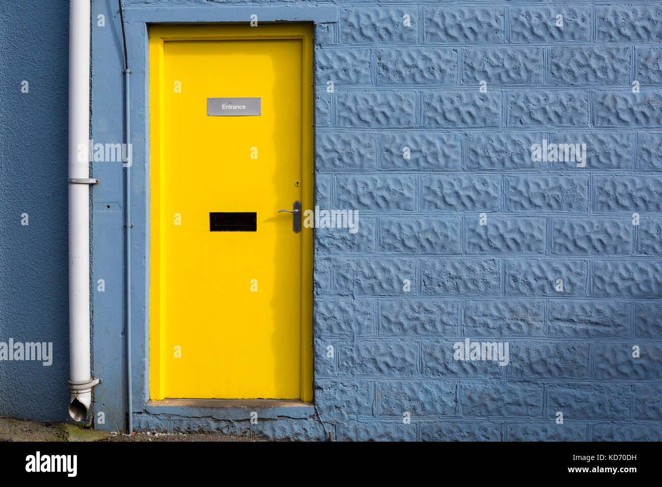 Bright colourful yellow door in blue wall Stock Photo