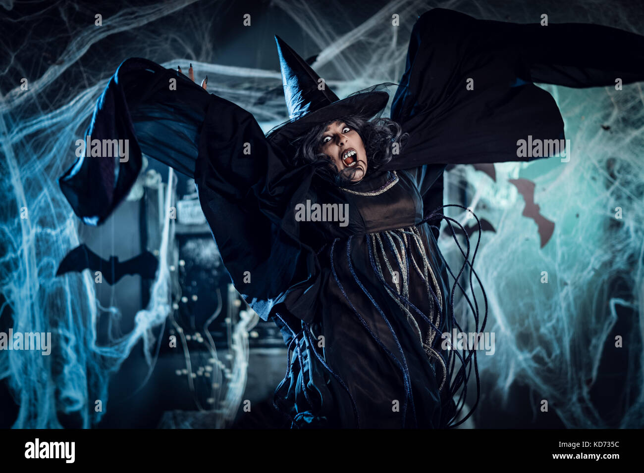 Witch with awfully face in creepy surrounding full of cobweb is dancing