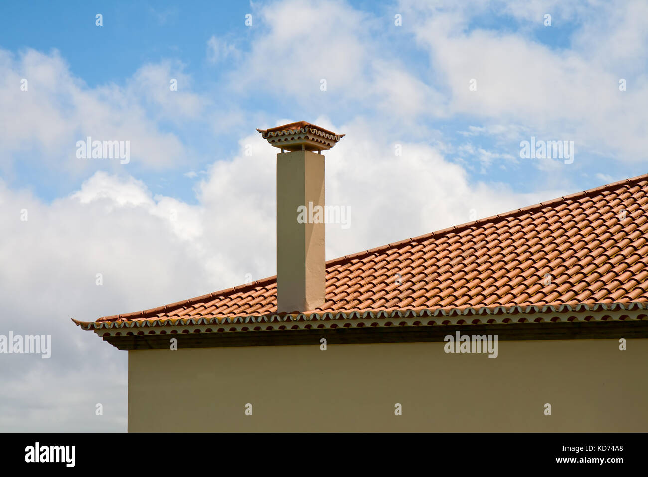 Fragment of a tiled roof with a ventilating pipe against the sky Stock Photo